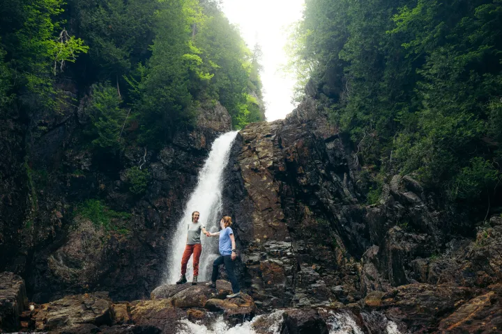 Two hikers in front of a waterfall.
