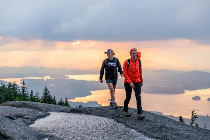 Two women walk across the top of a mountain in summer. 