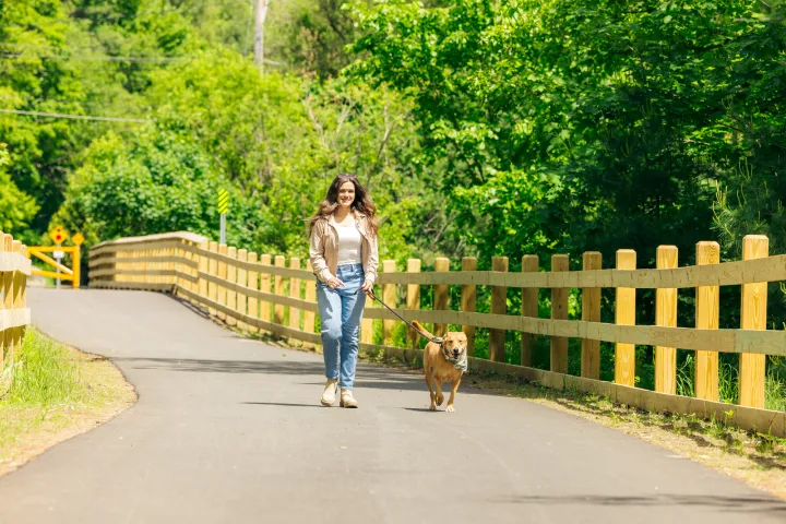 A woman walking her dog on the Rail Trail.