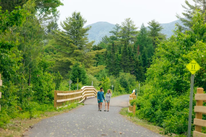A couple walking on the Adirondack Rail Trail in the summer.
