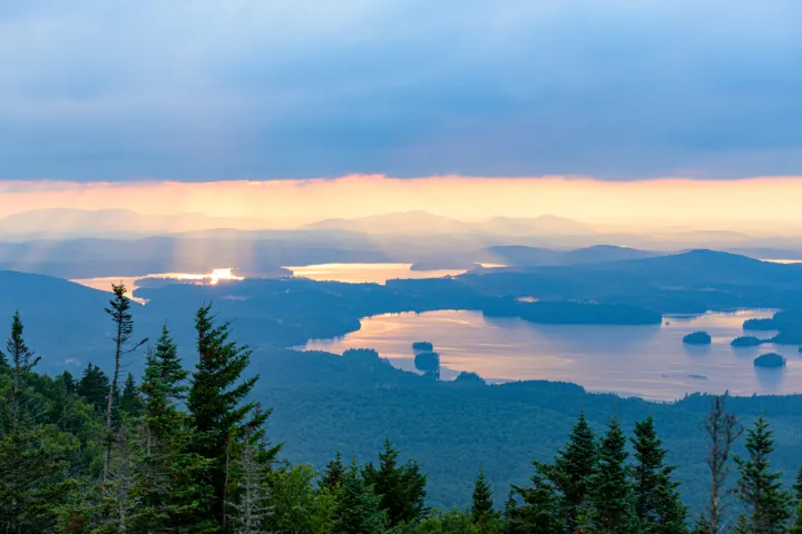 A view from a mountain looking down at a lake and surrounding mountains. 