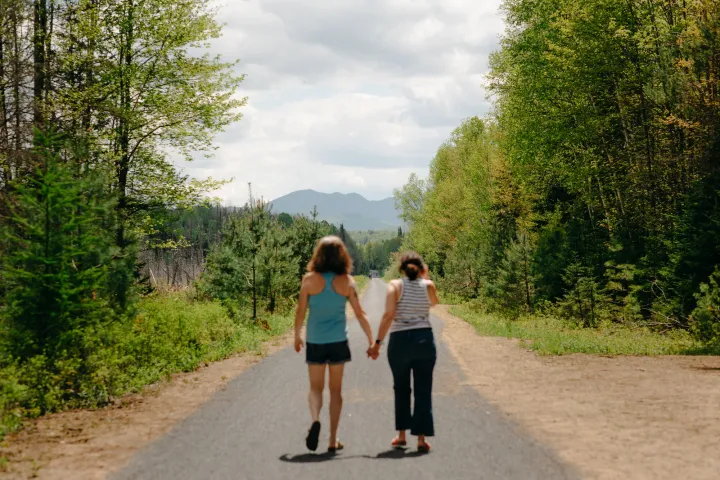 two women walk on a nature path in the wilderness. 