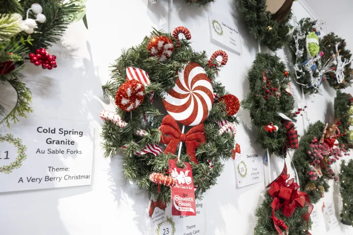 Close-up of decorated evergreen Christmas wreaths on a white wall.