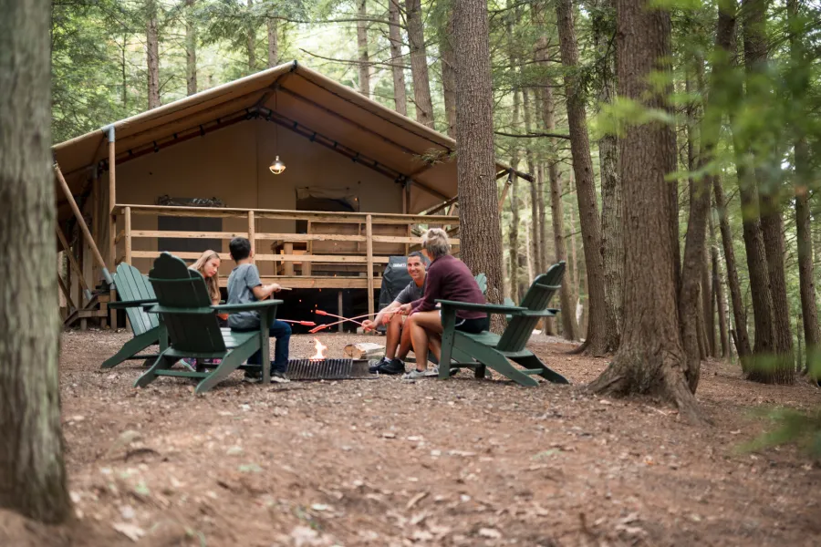 Campers at a small cabin sitting on Adirondack chairs