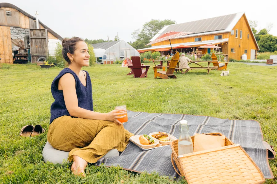 A woman enjoys a drink and picnic outside