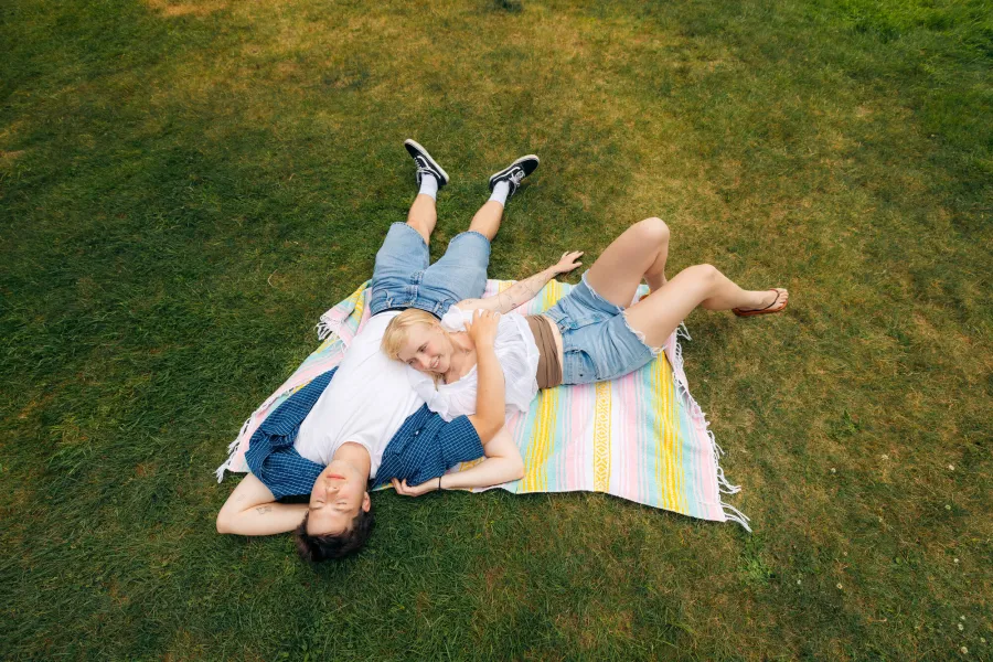 A couple lying on a blanket in the grass