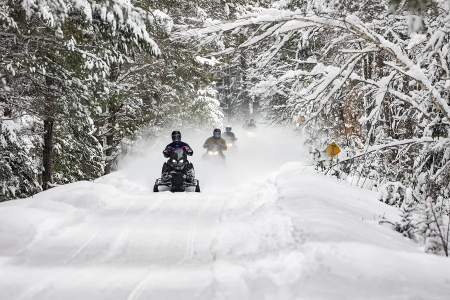 Snowmobilers on a snowed-in rail trail