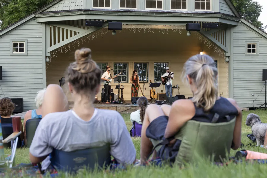 A huge bandshell wirth folks sitting on lawnchairs listening