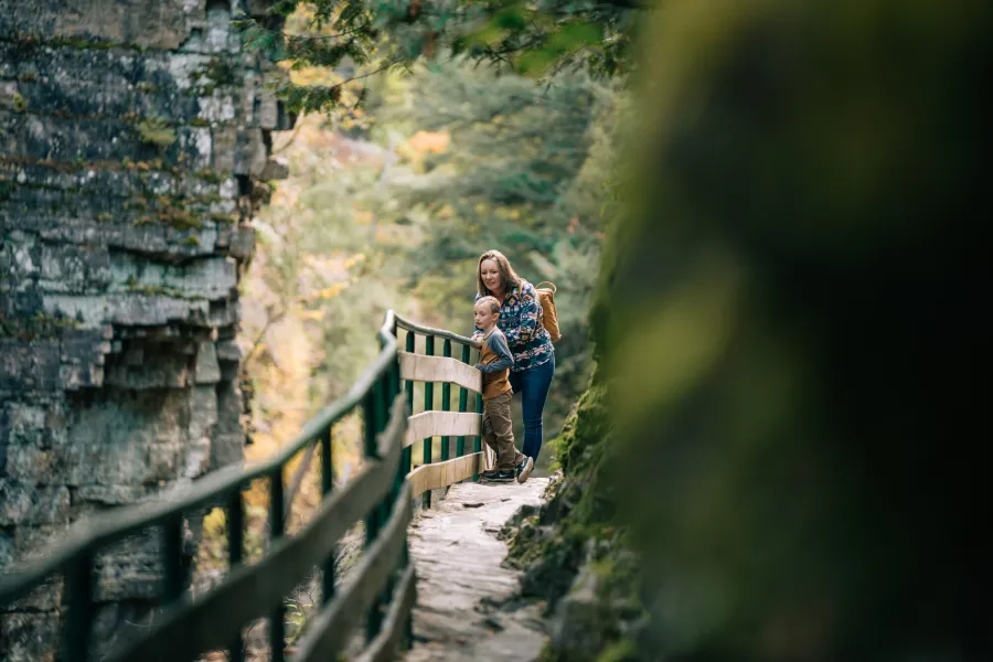 A mother and son walking through a chasm on a wooden walkway