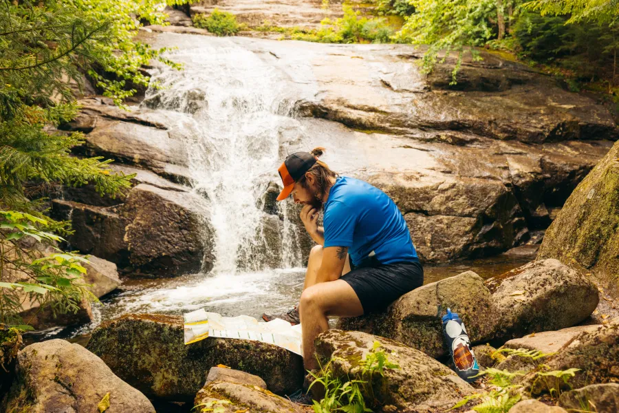 A man in front of a waterfall looking at a map