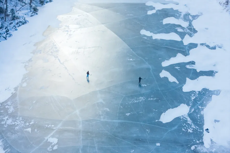 Two people skating on a frozen lake