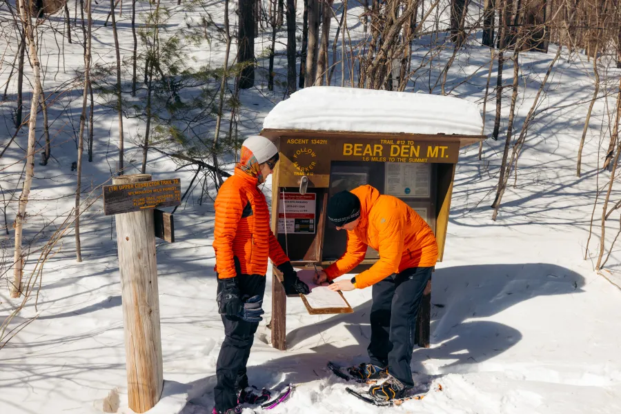 Two snowshoers signing a trail register