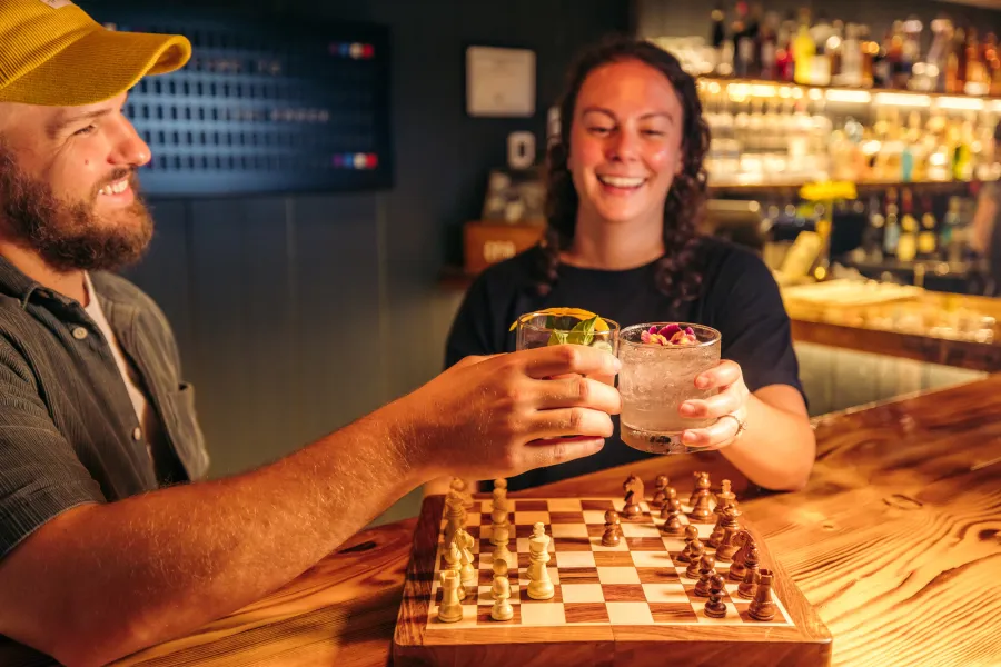 Two people drinking by a chess set