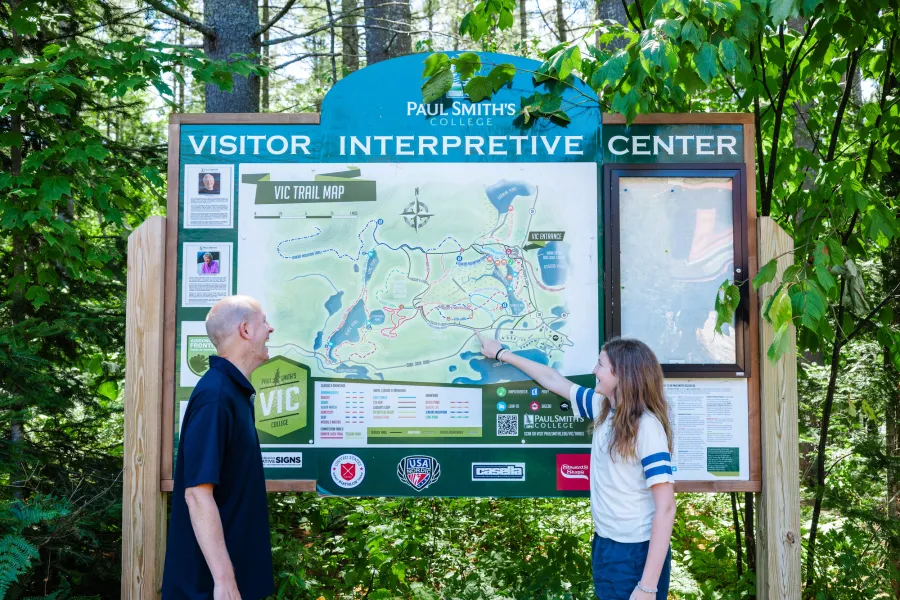 Two people in front of the wooden sign for Paul Smith's VIC