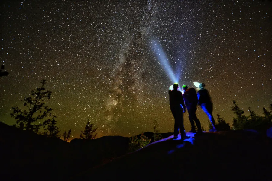 Three people viewing the night sky on a mountain