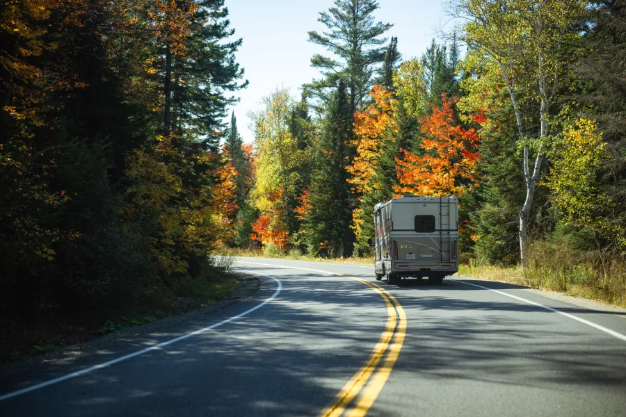An RV driving through fall scenery.