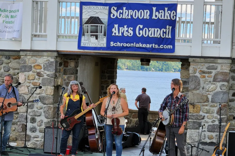 People playing music under a Schroon Lake Arts Council banner.