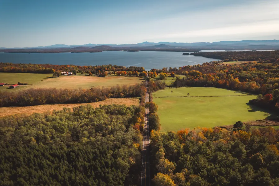 Aerial view of fields, a lake, and mountains during fall