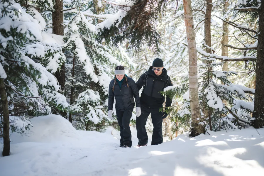 A man and woman in winter gear climb a mountain. 