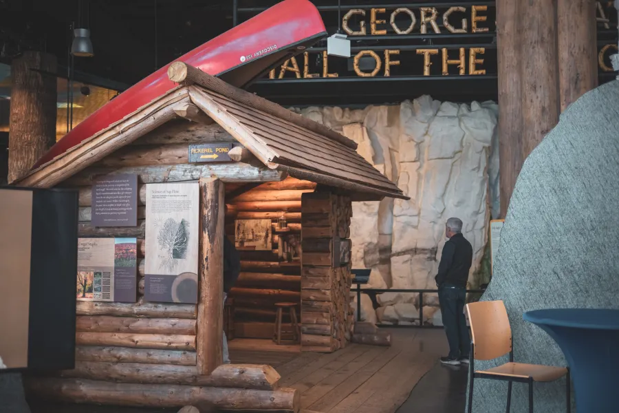 Someone in a museum exhibit with a wooden lean-to