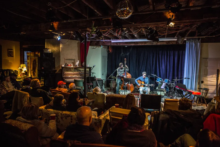 A small live performance space with people listening to live music