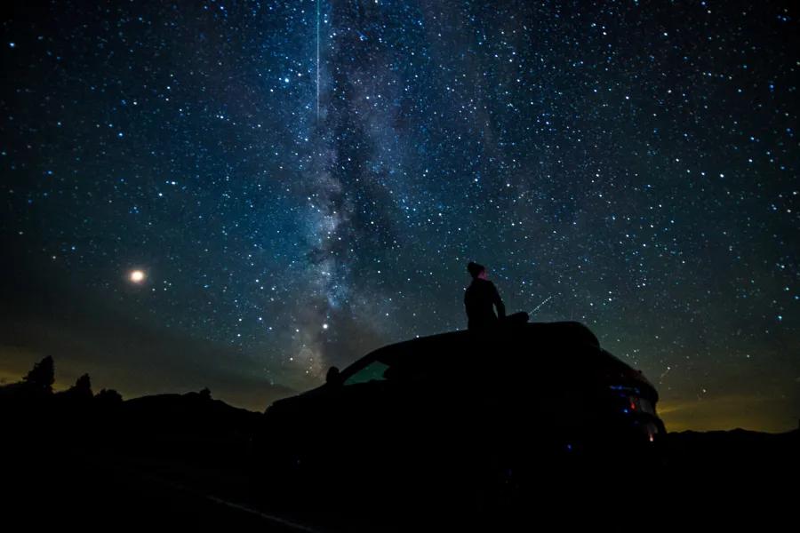 A person on top of their car looking at the stars