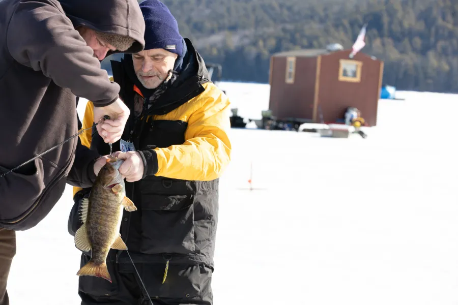 Two people with a smallmouth bass ice fishing