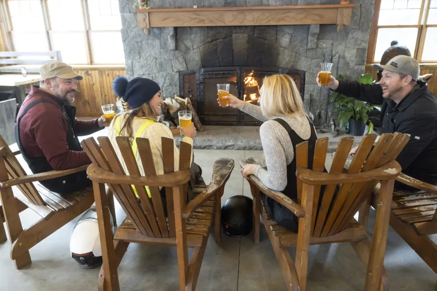 A group of snowmobilers drinking beer by a fire