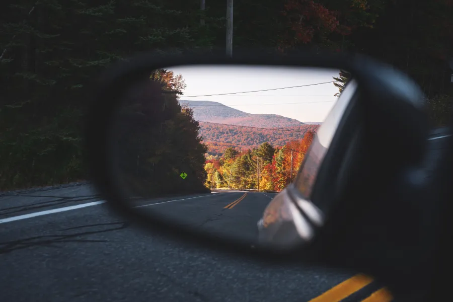 A side mirror of a car on a winding mountain road