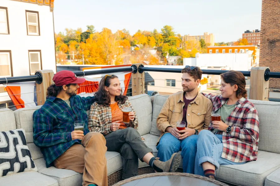 A group of four friends drinking beer on a patio in the fall