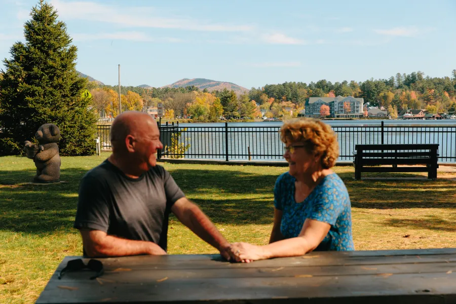 An older couple on a park bench by a lake