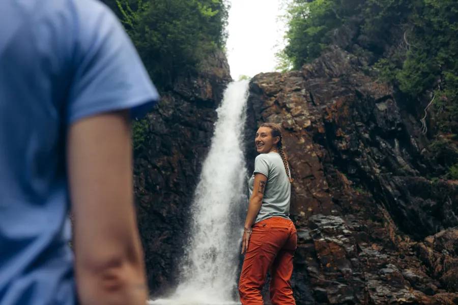 A woman standing near a massive plunging waterfall