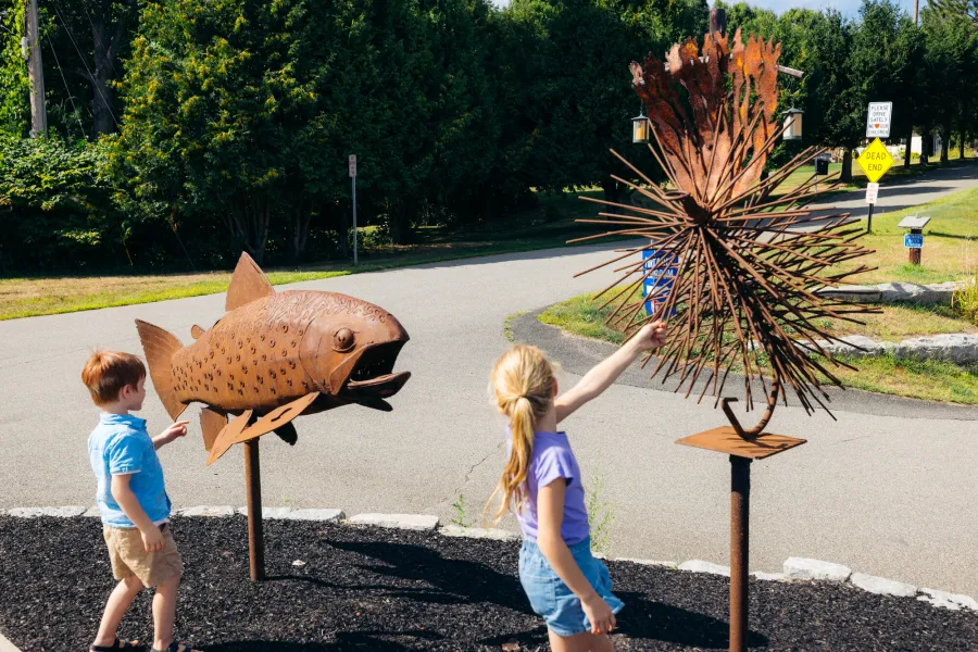 Kids at metal fishing art in Wilmington