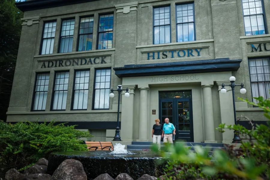 A man and woman walk from a gray historic building. 