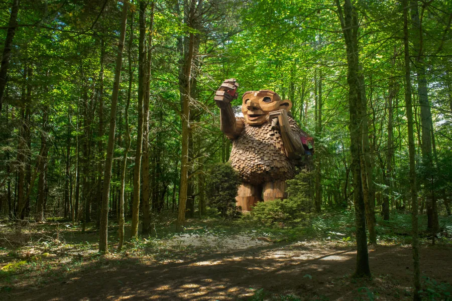 A troll statue stands in a forest. 