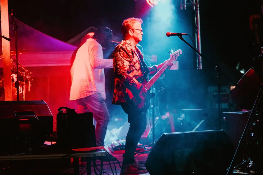 A guitar player is illuminated by red and blue stage lights.