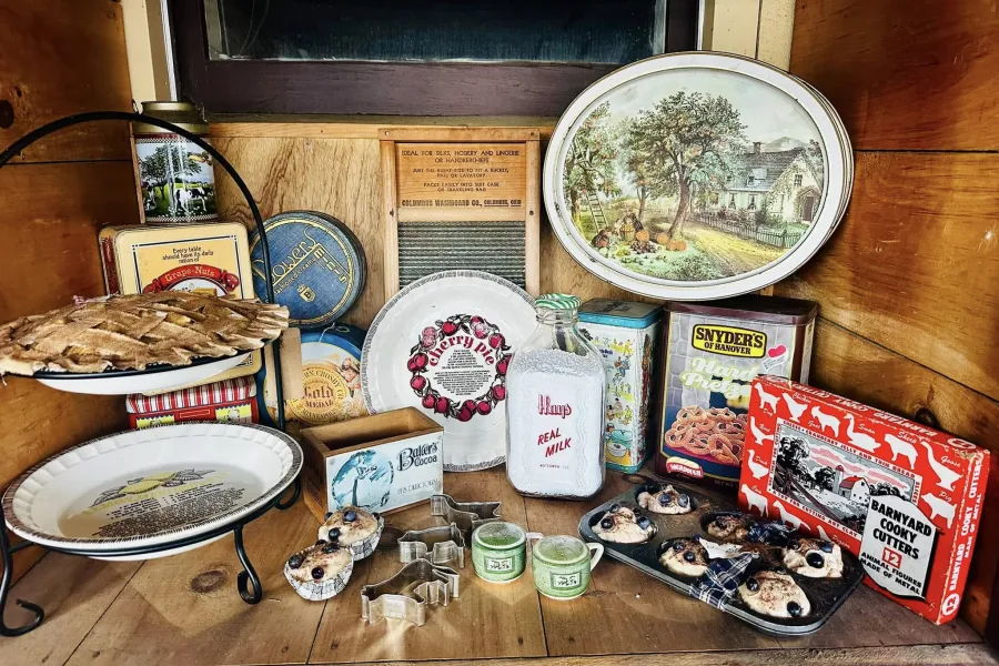 An array of antiques displayed in a vintage wooden crate, including dishes and trinkets.