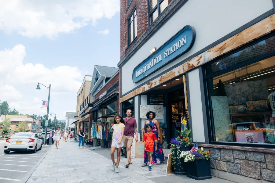 A family of four walks out of a toy shop in a small town. 