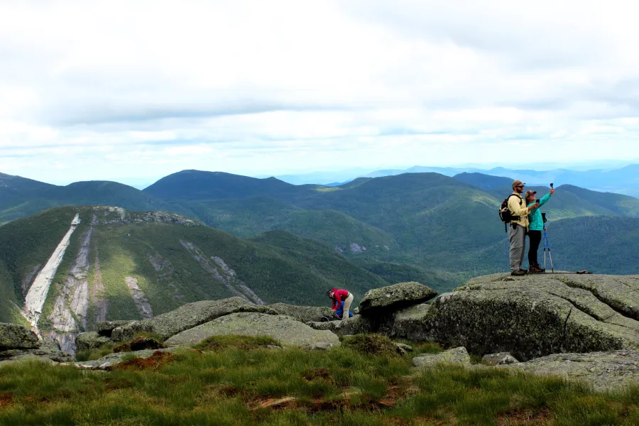 People take pictures on a mountain top in summer. 
