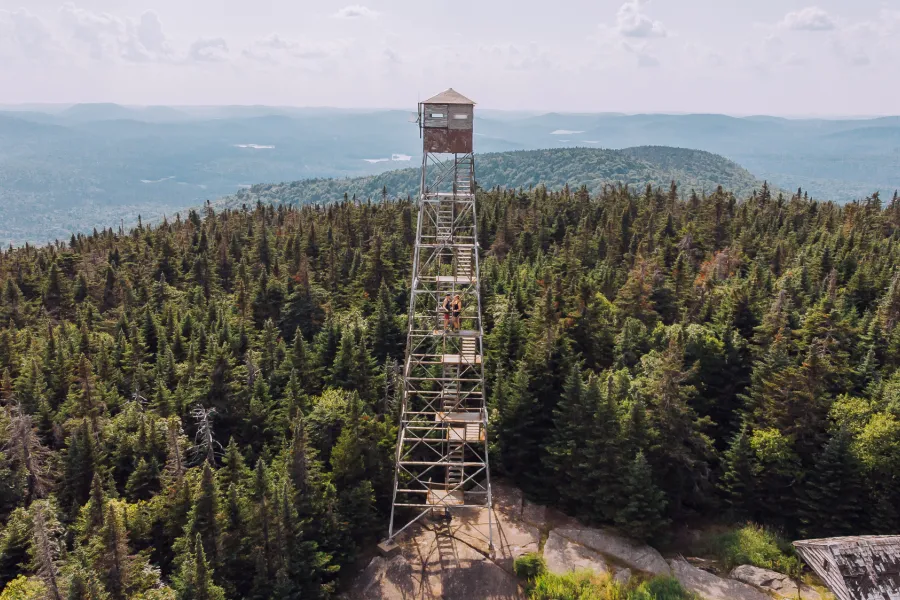 A firetower stands on top of a mountain in summer. 
